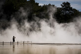 Distant Caucasian woman photographing geothermal pool
