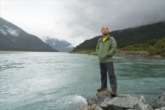 Chinese man standing on rock at river