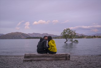 Mixed Race couple kissing on log at river