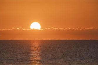Blazing sunrise in orange sky over ocean
