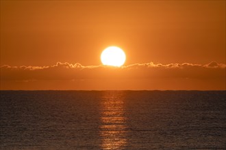 Blazing sunrise in orange sky over ocean