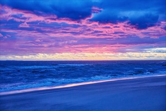 Beach and sea at sunset with dramatic blue and purple sky