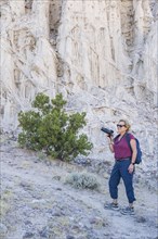 Woman with backpack and camera hiking in rocky landscape