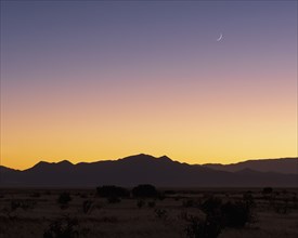 Crescent moon above Jemez Mountains at sunset