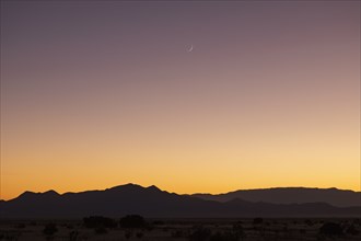 Crescent moon above Jemez Mountains at sunset