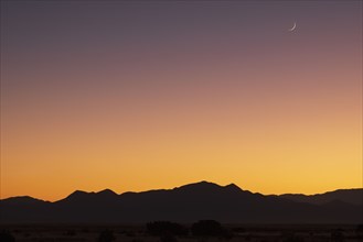 Crescent moon above Jemez Mountains at sunset