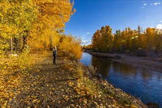 Senior woman walking along Big Wood river in Autumn