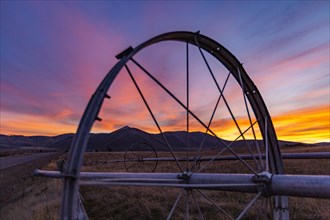 Close-up of irrigation wheel in field at sunset