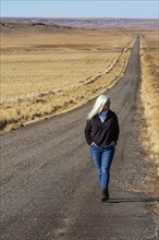 Senior woman walking down desert road
