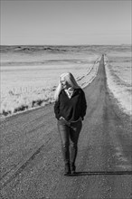 Senior woman walking down desert road