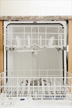 Empty open dishwasher in domestic kitchen