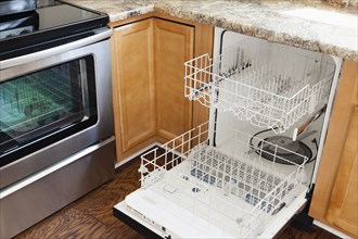 Empty open dishwasher in domestic kitchen
