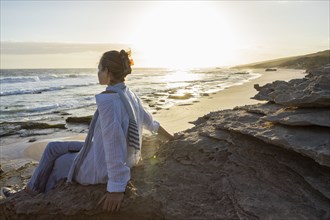 Girl sitting on beach at sunset