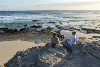 Mother and daughter sitting on beach