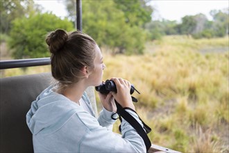 Girl in safari vehicle using binoculars