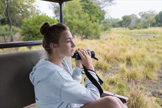 Girl in safari vehicle using binoculars