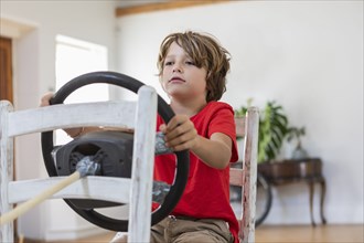 Boy playing with steering wheel in living room