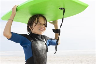 Boy carrying bodyboard on beach