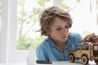Boy building wooden toy car at home
