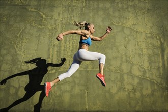 Athlete woman jumping against wall