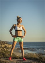 Athlete woman in sports clothing standing on beach