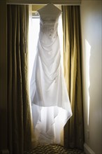 Wedding dress hanging against window