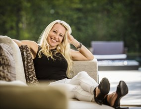 Portrait of smiling blond woman sitting on sofa