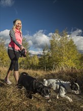 Smiling woman with two dogs walking in grassy field