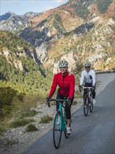 Smiling man and woman riding bicycles on mountain road