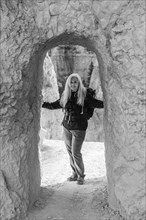 Senior female hiker standing in natural sandstone archway