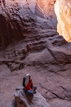 Senior female hiker sitting on rock in canyon