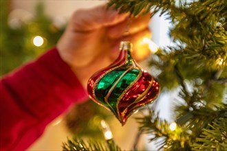 Hand hanging glass Christmas ornament on Christmas tree