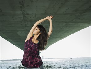 Woman stretching under bridge