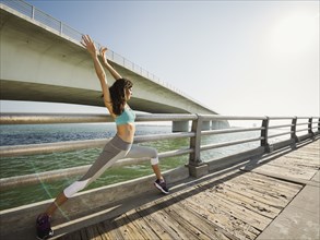 Woman stretching on bridge on sunny day
