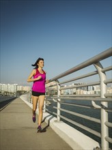 Woman jogging on bridge on sunny day