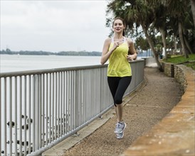 Woman jogging on footpath by river