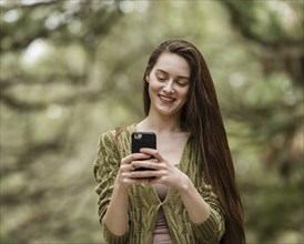 Smiling woman looking at smart phone in park