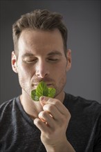 Studio shot of man smelling fresh mint leaves