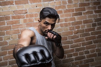 Portrait of man with boxing gloves against brick wall