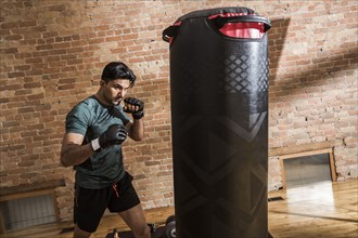 Man training with punching bag in gym