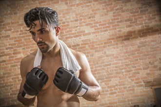Shirtless man with boxing gloves and towel in gym