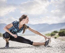 Woman stretching on road in desert landscape