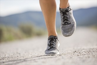 Close-up of feet of woman jogging in desert landscape
