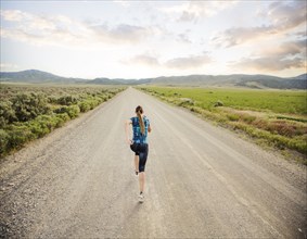 Rear view of woman jogging on road in desert landscape