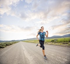 Woman jogging on road in desert landscape