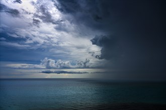 Dark thunderstorm clouds with rain over ocean