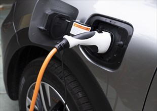 Close-up of electric car being charged with plug-in power cord