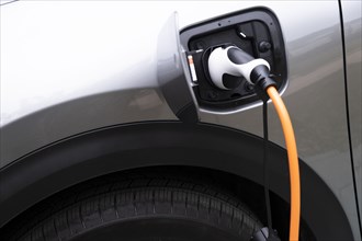 Close-up of electric car being charged with plug-in power cord