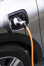 Close-up of electric car being charged with plug-in power cord