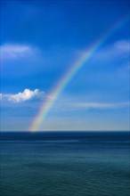 Rainbow over ocean against blue sky
